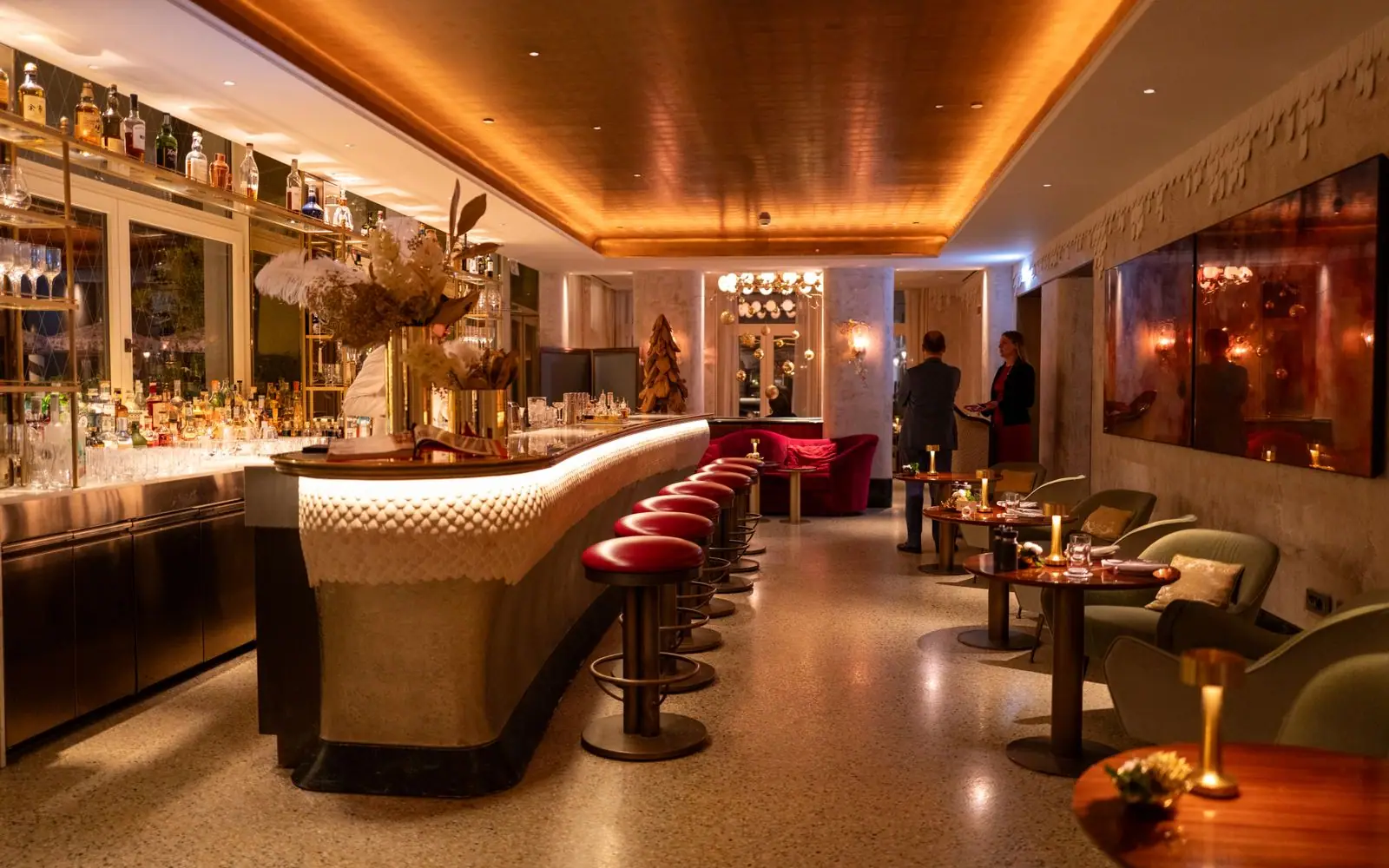 The hotel bar at golden hour, bottles glowing on dark shelving